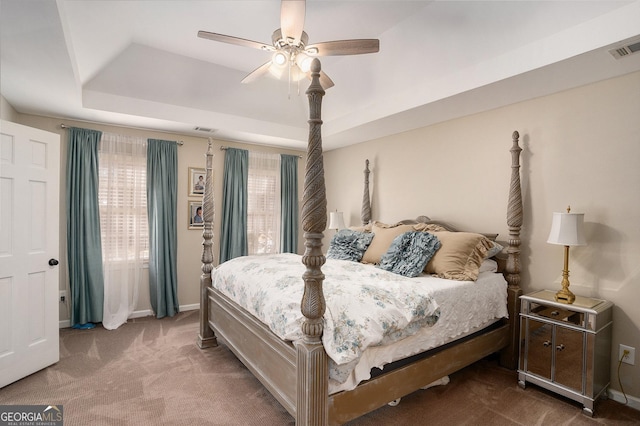 carpeted bedroom with a ceiling fan, a raised ceiling, baseboards, and visible vents