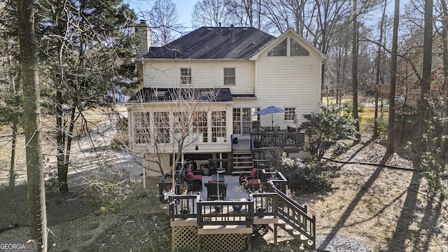 rear view of house with a deck, stairway, and a chimney