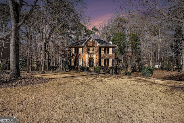 view of front facade with brick siding and a yard