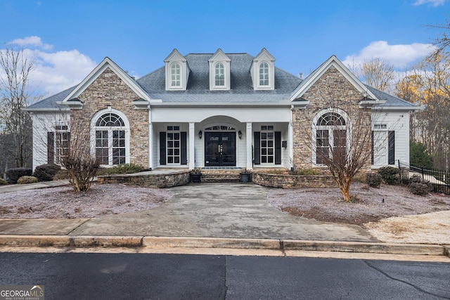 view of front of home featuring french doors, covered porch, and roof with shingles