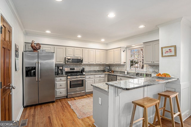 kitchen with visible vents, a peninsula, light wood-style flooring, a sink, and appliances with stainless steel finishes