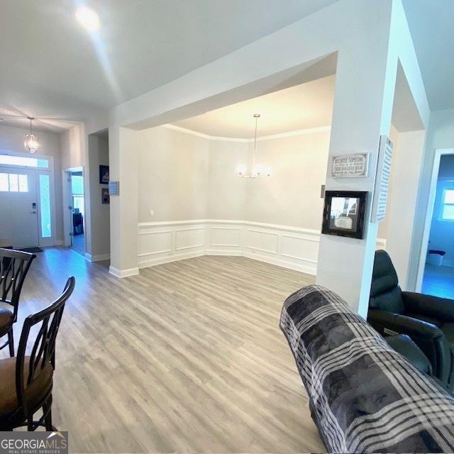 104 Eagle Heights Dr, Maysville, GA 30558 - living area featuring a wainscoted wall, a decorative wall, crown molding, wood finished floors, and an inviting chandelier