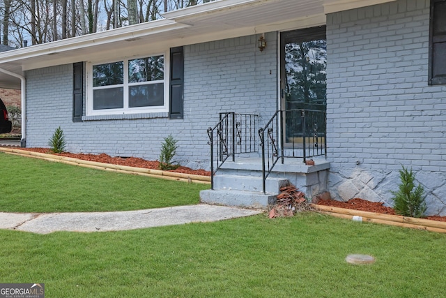 property entrance featuring brick siding and a lawn