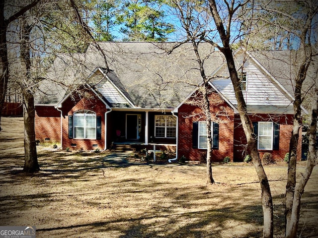 view of front of home featuring roof with shingles, brick siding, and crawl space