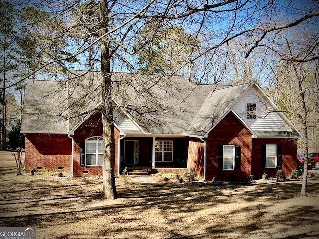 cape cod home with roof with shingles, brick siding, and crawl space