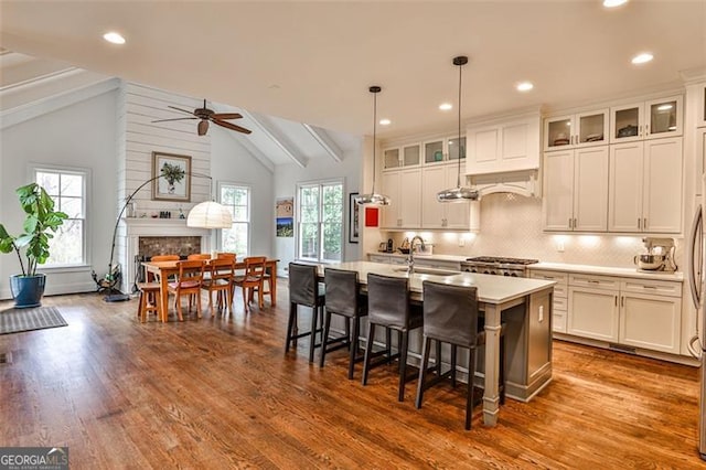 kitchen with lofted ceiling with beams, a fireplace, a sink, light countertops, and backsplash