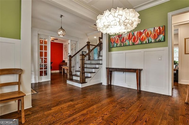 foyer with a decorative wall, wood finished floors, stairs, french doors, and ornamental molding