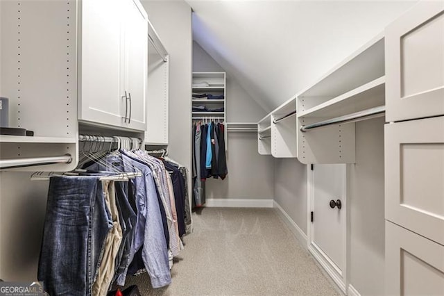 walk in closet with light carpet and lofted ceiling