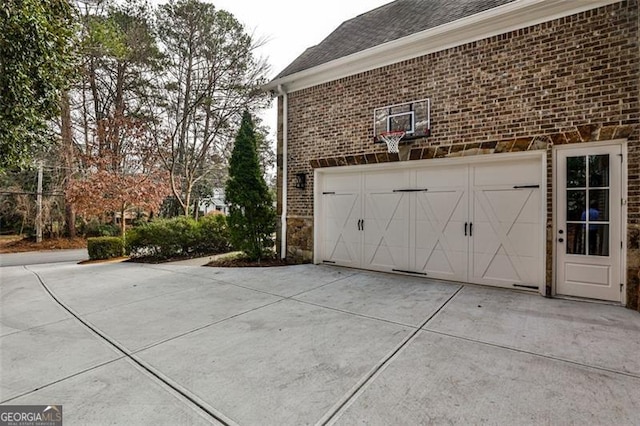 view of side of property featuring a garage, concrete driveway, and brick siding