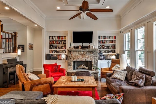 living area with ornamental molding, a fireplace, wood finished floors, and built in features