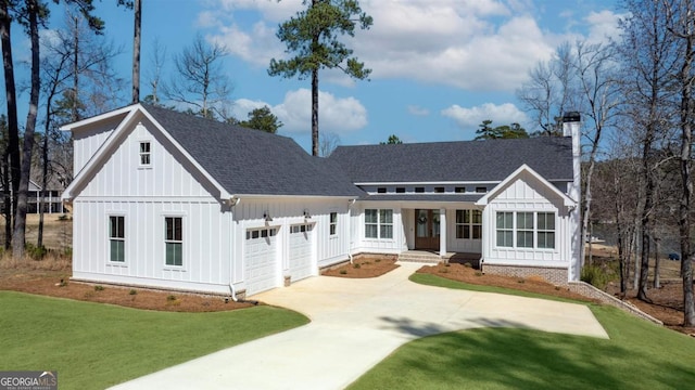 modern farmhouse style home with an attached garage, a shingled roof, a front lawn, and board and batten siding