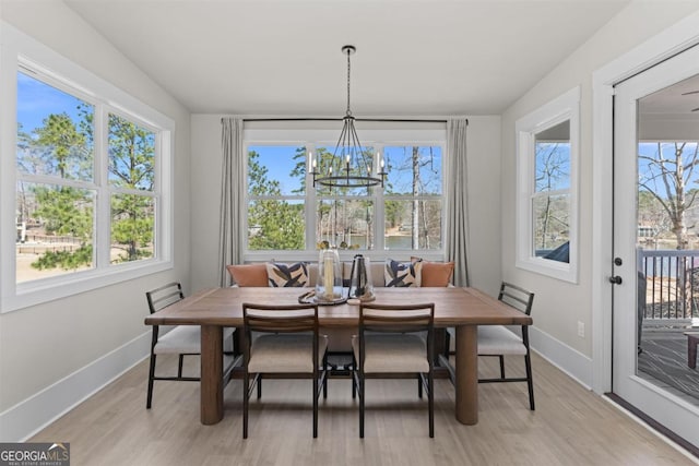 dining room with light wood-style floors, breakfast area, a notable chandelier, and baseboards