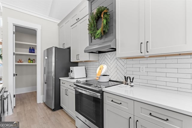 kitchen with appliances with stainless steel finishes, light countertops, light wood-style flooring, and exhaust hood