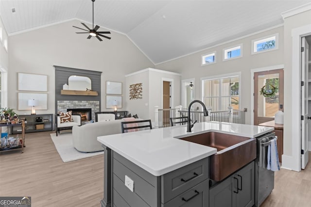 kitchen with ceiling fan, a stone fireplace, light countertops, gray cabinetry, and a sink