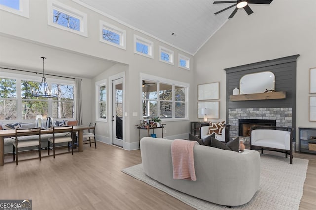 living area featuring high vaulted ceiling, baseboards, light wood-type flooring, a brick fireplace, and crown molding