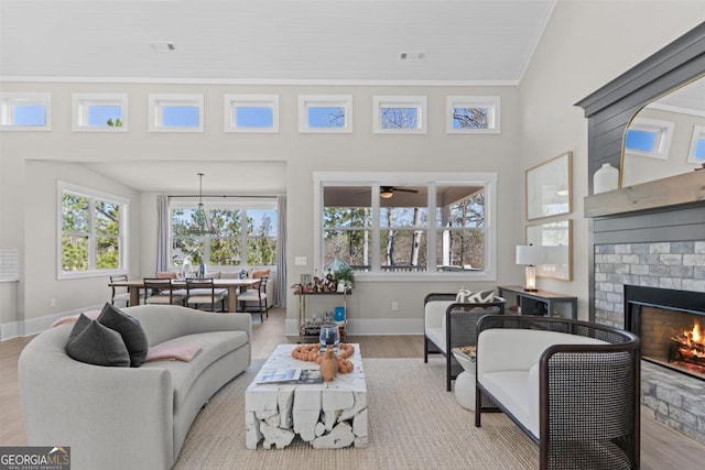 living area featuring a fireplace, wood finished floors, visible vents, baseboards, and ornamental molding