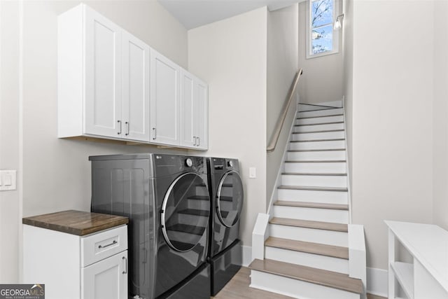 laundry room featuring cabinet space, washer and clothes dryer, baseboards, and wood finished floors