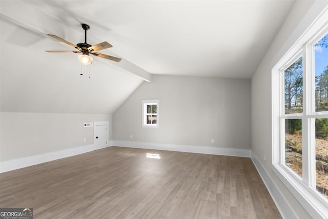 additional living space with visible vents, baseboards, a ceiling fan, vaulted ceiling with beams, and light wood-type flooring