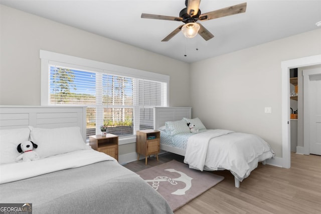 bedroom featuring ceiling fan, light wood-style flooring, and baseboards