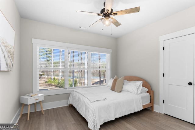 bedroom featuring baseboards, multiple windows, visible vents, and wood finished floors