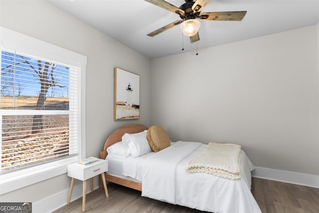 bedroom with ceiling fan, wood finished floors, and baseboards