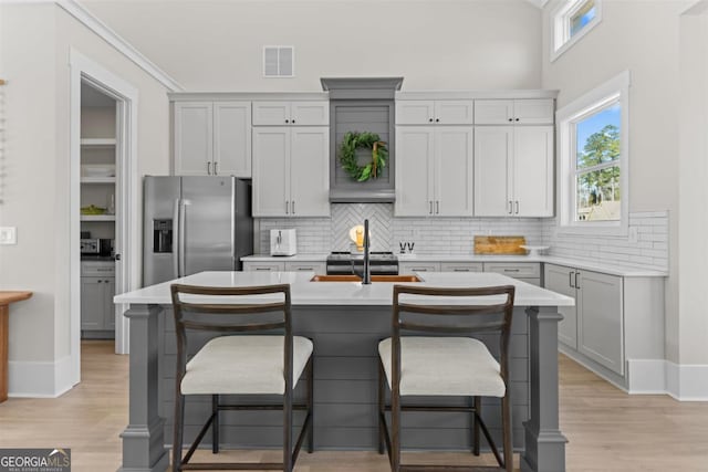 kitchen featuring light wood finished floors, stainless steel refrigerator with ice dispenser, a sink, and light countertops