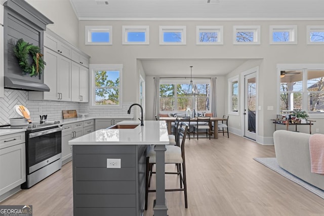 kitchen featuring decorative backsplash, a kitchen breakfast bar, stainless steel electric stove, light countertops, and a sink