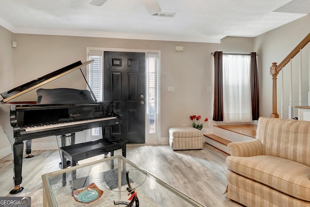 sitting room with crown molding, visible vents, wood finished floors, baseboards, and stairs