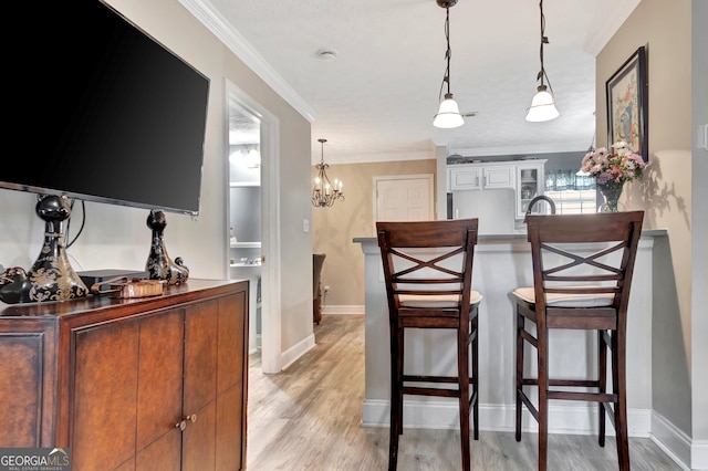 dining room with baseboards, light wood-type flooring, a chandelier, and crown molding