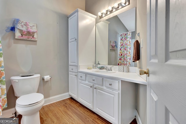 bathroom with toilet, baseboards, wood finished floors, and vanity