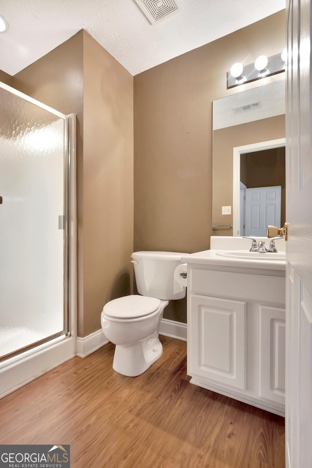 full bath featuring toilet, a stall shower, visible vents, and wood finished floors