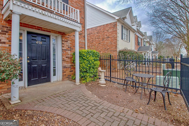 view of property exterior featuring a balcony, fence, and brick siding