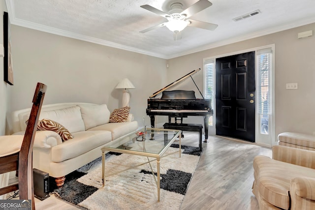 living room with ornamental molding, visible vents, and wood finished floors