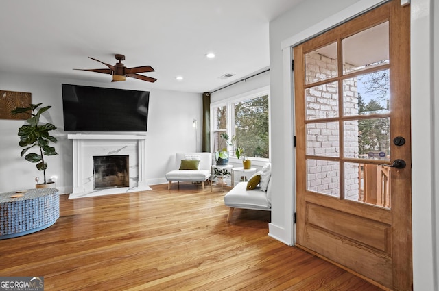 sitting room with recessed lighting, visible vents, a ceiling fan, a high end fireplace, and wood finished floors