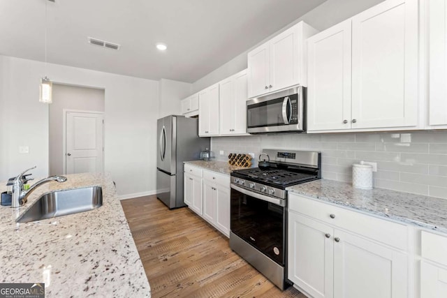 kitchen with a sink, visible vents, white cabinets, appliances with stainless steel finishes, and tasteful backsplash