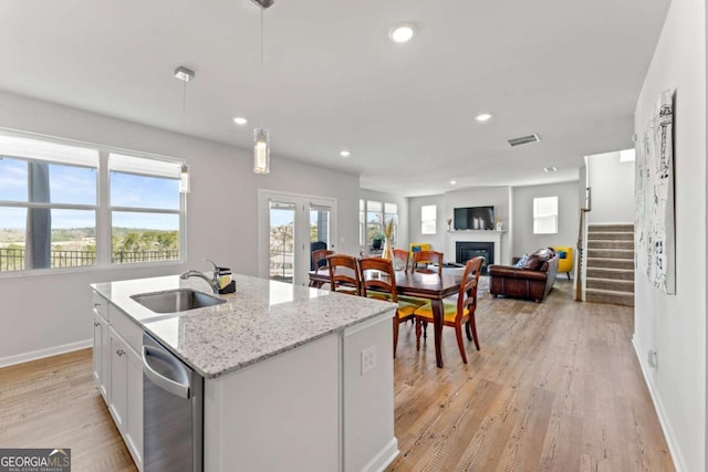 kitchen with dishwasher, light wood-style floors, a fireplace, a sink, and recessed lighting