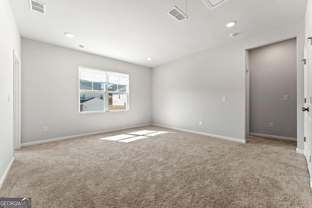 carpeted empty room with baseboards, visible vents, and attic access