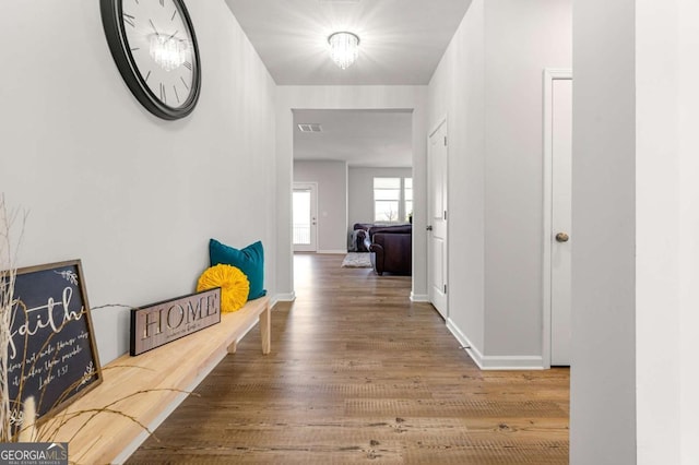 corridor with baseboards, visible vents, and wood finished floors