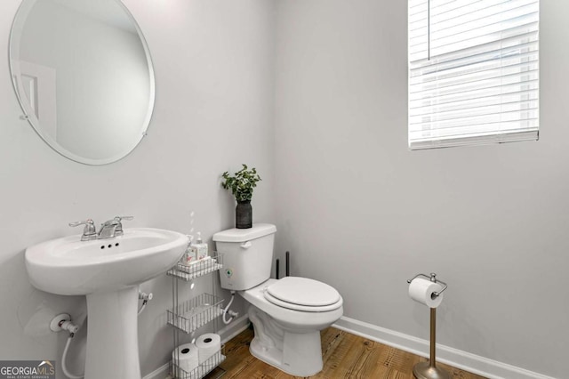 half bathroom with a sink, wood finished floors, toilet, and baseboards