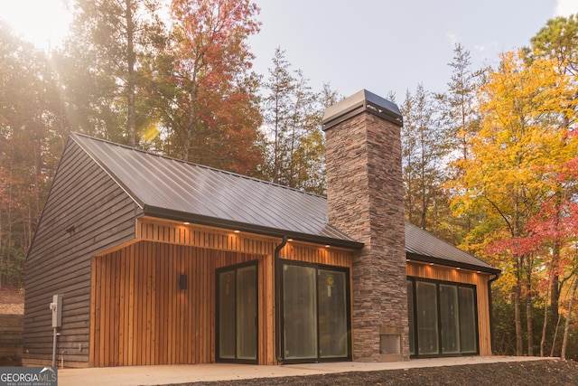 back of house featuring metal roof and a chimney