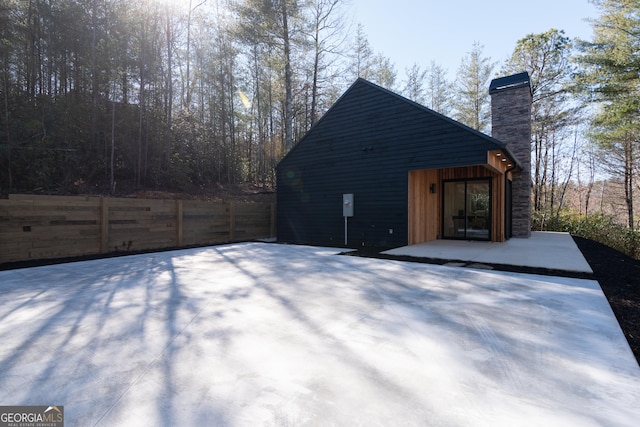 view of property exterior featuring a patio area, a chimney, and fence