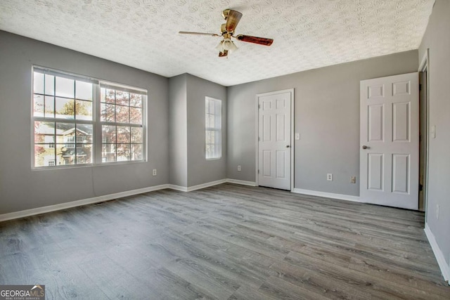 spare room featuring ceiling fan, a textured ceiling, baseboards, and wood finished floors