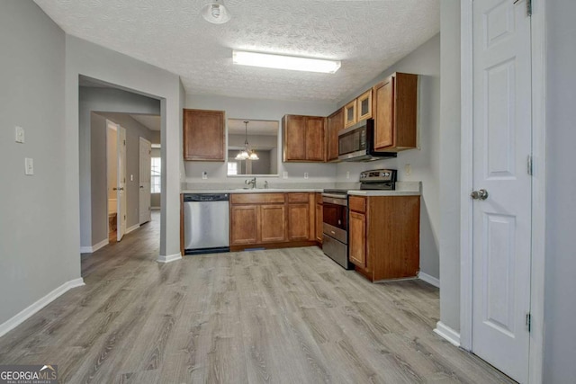 kitchen with baseboards, brown cabinetry, light wood-style flooring, appliances with stainless steel finishes, and light countertops