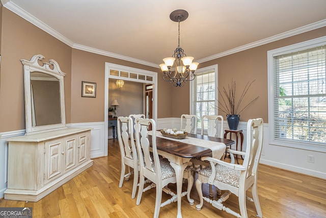 dining room featuring a wainscoted wall, ornamental molding, and an inviting chandelier