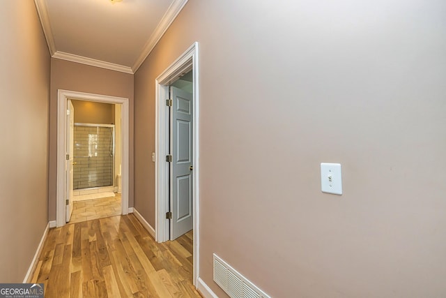 hall with baseboards, visible vents, light wood-style flooring, and crown molding