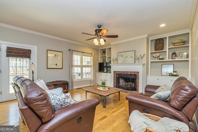 living room with a healthy amount of sunlight, light wood-type flooring, a fireplace, and ornamental molding