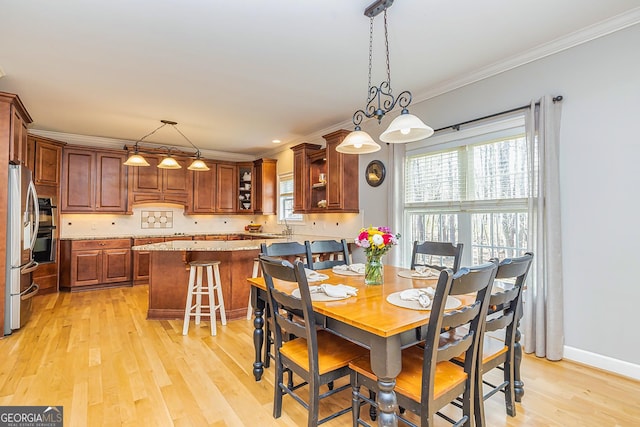 dining area featuring baseboards, ornamental molding, and light wood-style floors