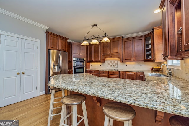 kitchen featuring stainless steel fridge, light wood-style flooring, light stone counters, a peninsula, and a sink