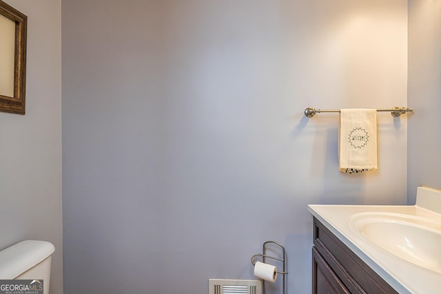 half bath with toilet, vanity, and visible vents