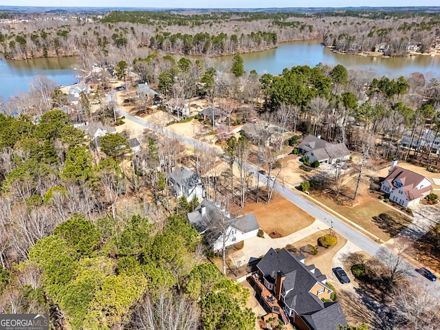 birds eye view of property featuring a water view and a wooded view